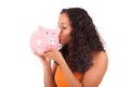 Young african american woman kissing piggy bank Royalty Free Stock Photo