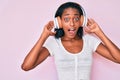 Young african american woman listening to music using headphones celebrating crazy and amazed for success with open eyes screaming Royalty Free Stock Photo