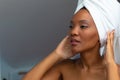 Young african american woman looking away while adjusting her head towel in bathroom, copy space Royalty Free Stock Photo