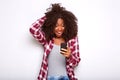 Young african american woman looking at mobile phone with surprised expression on white background Royalty Free Stock Photo