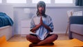 Young african american woman meditating on yoga mat in her bedroom. wellbeing concept Royalty Free Stock Photo