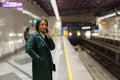 Young african american woman making mobile phone call while waiting for train at subway platform Royalty Free Stock Photo