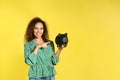 Young African-American woman with piggy bank on color background. Money saving Royalty Free Stock Photo