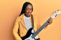 Young african american woman playing electric guitar winking looking at the camera with sexy expression, cheerful and happy face Royalty Free Stock Photo