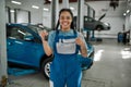 Best service here. Young african american woman, professional female mechanic smiling at camera, giving car key and Royalty Free Stock Photo