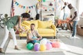 young african american woman proposing party hat to smiling man on floor with balloons and woman