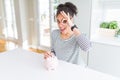 Young african american woman putting a coin inside piggy bank as invest or saving with happy face smiling doing ok sign with hand Royalty Free Stock Photo