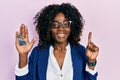 Young african american woman real state agent holding key of house smiling with an idea or question pointing finger with happy