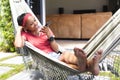 Young African American woman relaxes in a hammock, browsing her phone Royalty Free Stock Photo