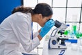 Young african american woman scientist using microscope at laboratory Royalty Free Stock Photo