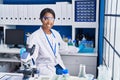 Young african american woman scientist using microscope working at laboratory Royalty Free Stock Photo