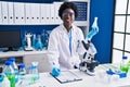 Young african american woman scientist writing on document measuring liquid at laboratory Royalty Free Stock Photo