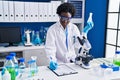 Young african american woman scientist writing on document measuring liquid at laboratory Royalty Free Stock Photo