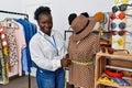 Young african american woman shopkeeper measuring manikin clothes at clothing store