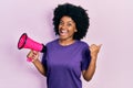 Young african american woman shouting through megaphone pointing thumb up to the side smiling happy with open mouth Royalty Free Stock Photo