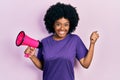 Young african american woman shouting through megaphone screaming proud, celebrating victory and success very excited with raised Royalty Free Stock Photo