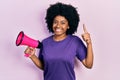 Young african american woman shouting through megaphone smiling with an idea or question pointing finger with happy face, number Royalty Free Stock Photo