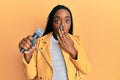 Young african american woman singing song using microphone covering mouth with hand, shocked and afraid for mistake Royalty Free Stock Photo