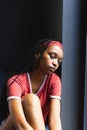 A young African American woman sits contemplatively by a window Royalty Free Stock Photo