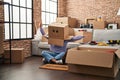 Young african american woman sitting on the floor with funny cardboard box on head at new home