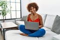 Young african american woman sitting on the sofa at home using laptop with a happy and cool smile on face Royalty Free Stock Photo