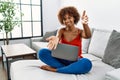 Young african american woman sitting on the sofa at home using laptop looking at the camera smiling with open arms for hug Royalty Free Stock Photo