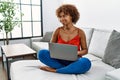 Young african american woman sitting on the sofa at home using laptop smiling looking to the side and staring away thinking Royalty Free Stock Photo