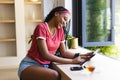 A young African American woman smiles while using a tablet Royalty Free Stock Photo