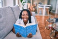 Young african american woman smiling happy laying on the sofa reading book at home