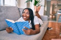 Young african american woman smiling happy laying on the sofa reading book at home Royalty Free Stock Photo