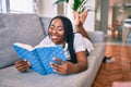 Young african american woman smiling happy laying on the sofa reading book at home Royalty Free Stock Photo