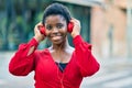 Young african american woman smiling happy listening to music using headphones at the city Royalty Free Stock Photo