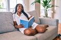 Young african american woman smiling happy reading book at home Royalty Free Stock Photo