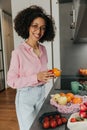 Young african american woman smiling looking at camera preparing salad in kitchen interior. Royalty Free Stock Photo