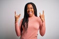 Young african american woman standing casual and cool over white isolated background shouting with crazy expression doing rock Royalty Free Stock Photo