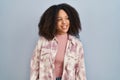 Young african american woman standing over blue background looking away to side with smile on face, natural expression Royalty Free Stock Photo