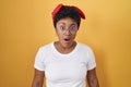 Young african american woman standing over yellow background afraid and shocked with surprise and amazed expression, fear and Royalty Free Stock Photo