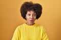 Young african american woman standing over yellow background afraid and shocked with surprise expression, fear and excited face Royalty Free Stock Photo