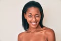 Young african american woman standing topless showing skin winking looking at the camera with sexy expression, cheerful and happy Royalty Free Stock Photo