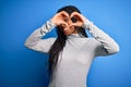 Young african american woman standing wearing casual turtleneck over blue isolated background Doing heart shape with hand and