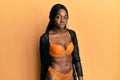 Young african american woman standing wearing sexy lingerie and posing with serious and seductive face over yellow background Royalty Free Stock Photo