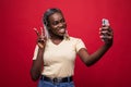 Young African American woman taking a selfie isolated on red background Royalty Free Stock Photo