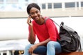 Young african american woman talking on cellphone while sitting down in the city with bag Royalty Free Stock Photo