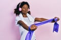 Young african american woman training arm resistance with elastic arm bands using headphones looking at the camera blowing a kiss Royalty Free Stock Photo