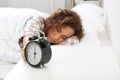 Young African-American woman turning off alarm clock Royalty Free Stock Photo