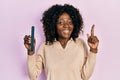 Young african american woman using file nail smiling with an idea or question pointing finger with happy face, number one