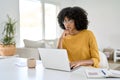 Young African American woman using laptop computer sitting at home table. Royalty Free Stock Photo