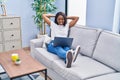 Young african american woman using laptop sitting on sofa at home Royalty Free Stock Photo
