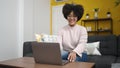 Young african american woman using laptop sitting on sofa at home Royalty Free Stock Photo