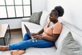 Young african american woman using laptop sitting on sofa at home Royalty Free Stock Photo